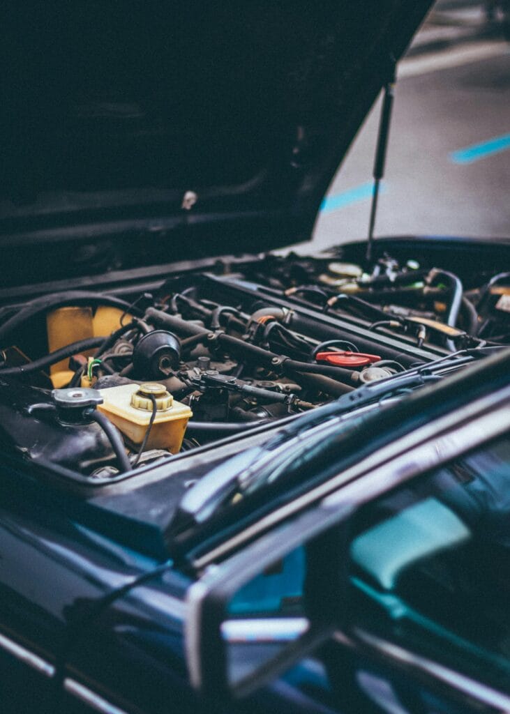 An open car bonnet during routine vehicle maintenance in Kenya, showing engine components being inspected.