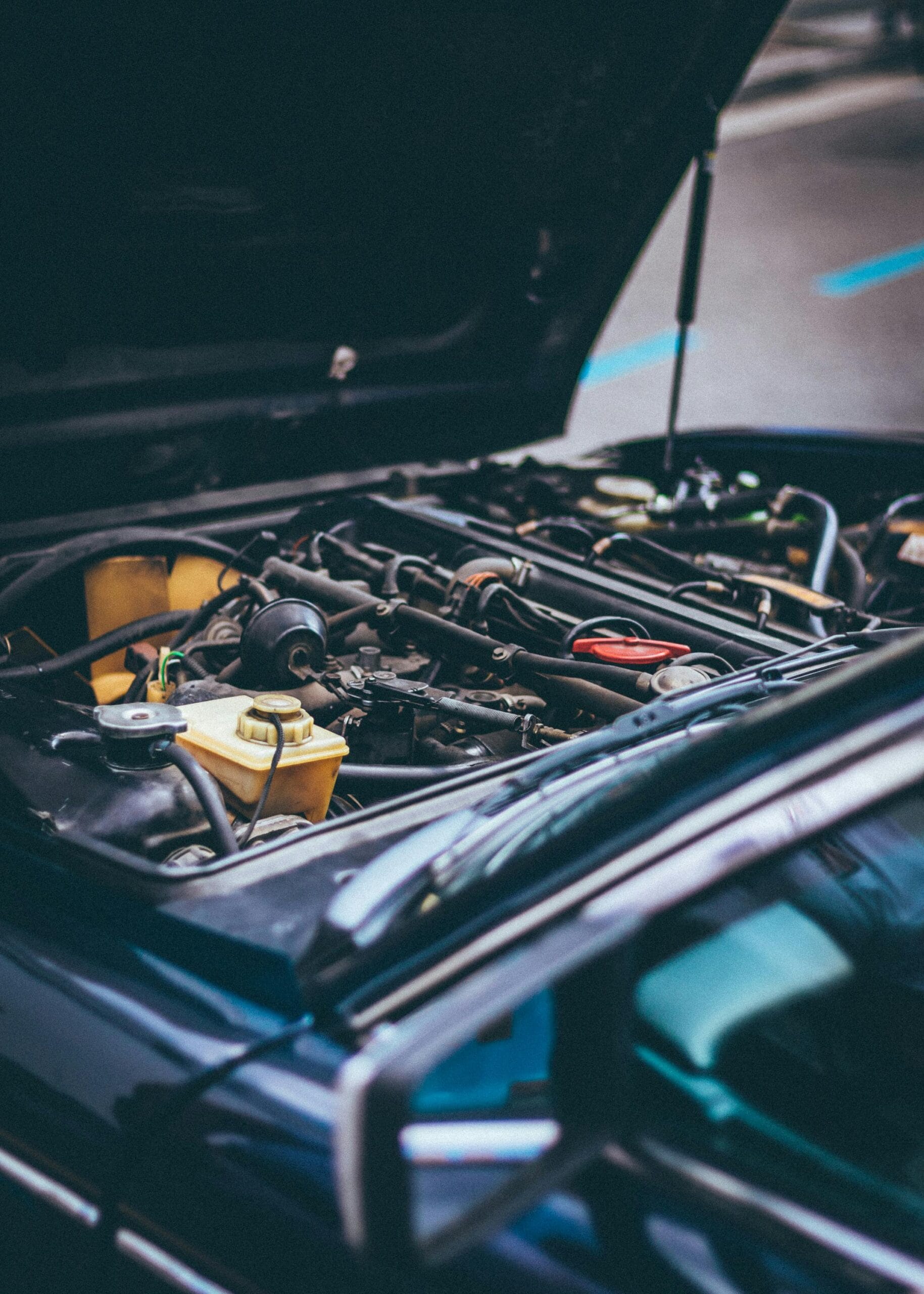 An open car bonnet during routine vehicle maintenance in Kenya, showing engine components being inspected.