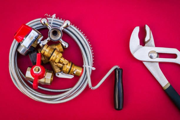 Plumbing tools, cable for connecting water hoses on red background