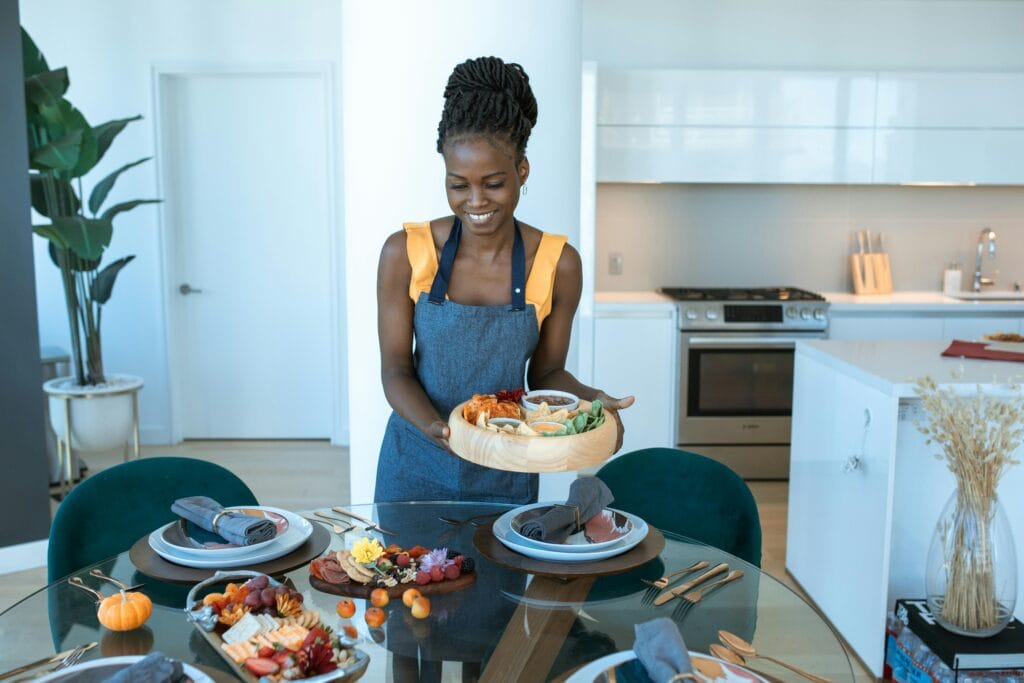 caterer serving a fresh appetizer platter at a budget-friendly private dining setup in a modern kitchen.