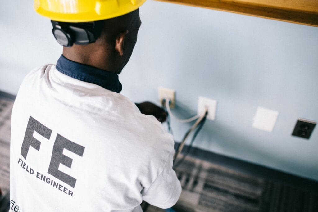 An electrician using tools to fix wall sockets during a home electrical repair job in Kenya.