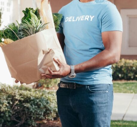 Smiling errand runner delivering groceries to a customer’s doorstep