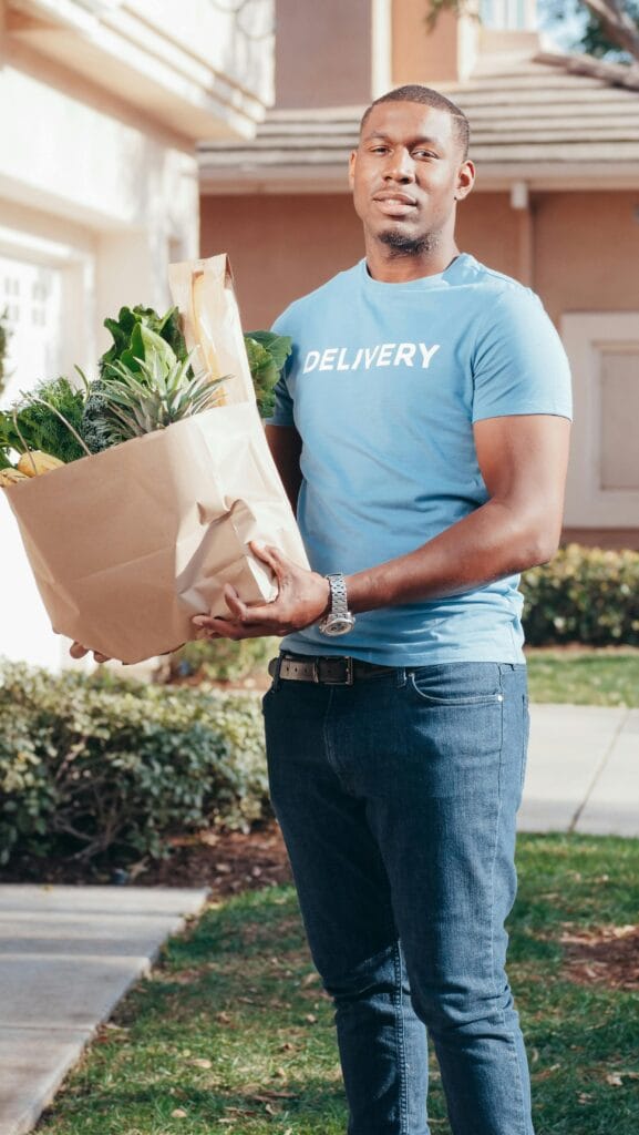 Smiling errand runner delivering groceries to a customer’s doorstep