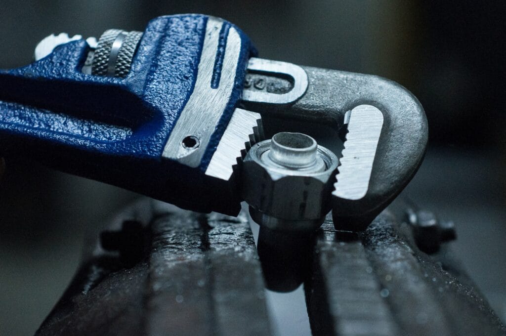 A closeup shot of a pipe wrench screwing a nut