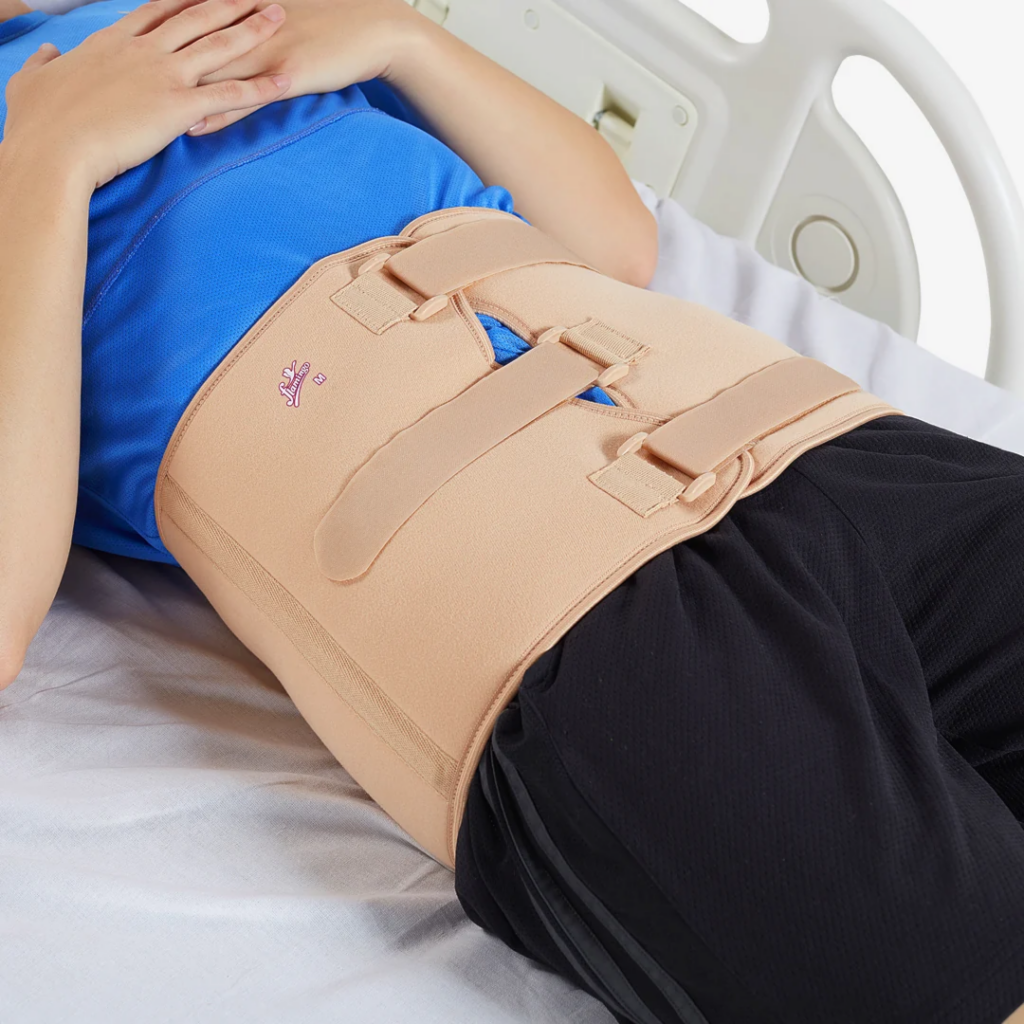 Person lying on hospital bed wearing beige abdominal and back support brace with adjustable Velcro straps Nairobi Kenya.